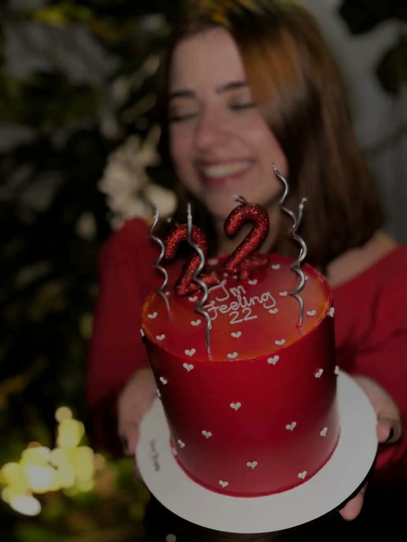 Confeiteira sorrindo com bolo vermelho de aniversário